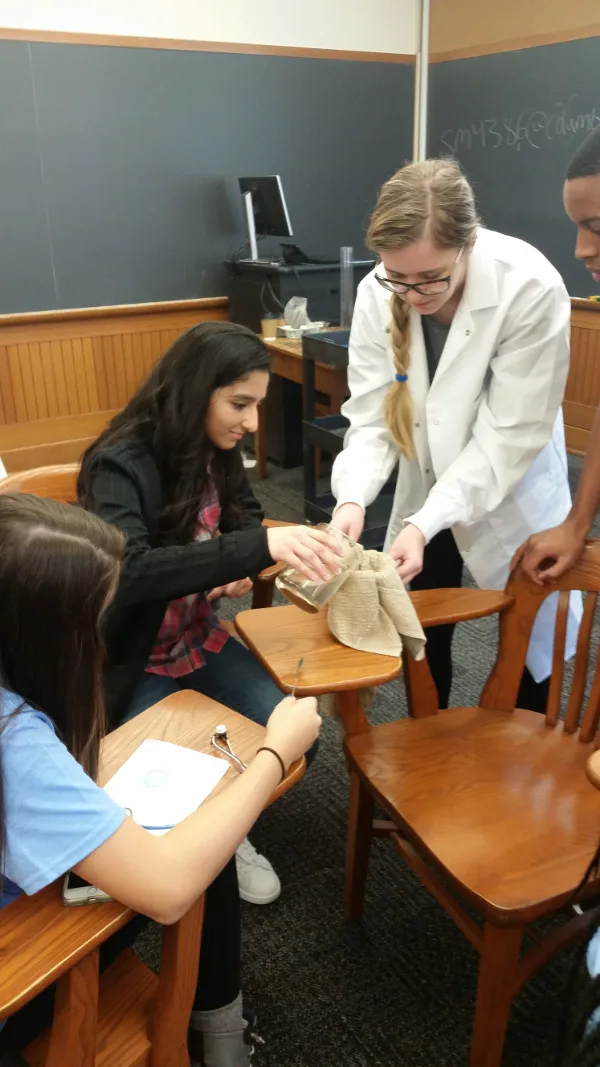 The high school students get hands-on and purify a beaker of contaminated water