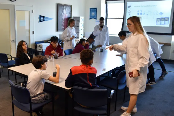 Natalie, Omar, Amar, and Steph (in lab coats, left to right) explains water quality and point-of-use water treatment